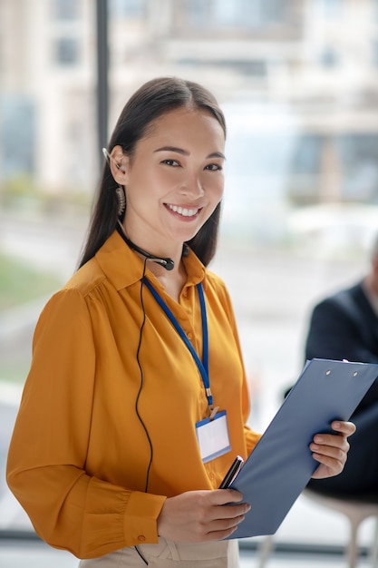 Jovem, linda mulher asiática com um distintivo sorrindo bem