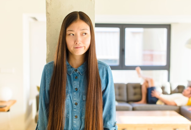 Jovem, linda mulher asiática, parecendo perplexa e confusa, pensando ou tentando resolver um problema ou pensamento