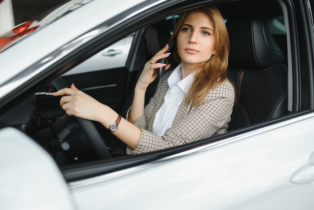 Jovem linda mulher de negócios sentada no carro