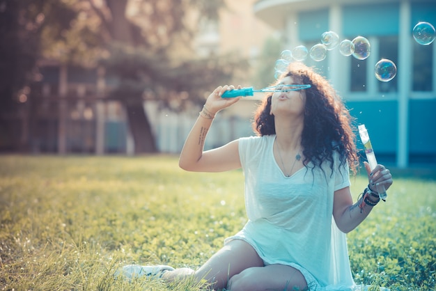 jovem linda mulher encaracolada marroquina soprando bolhas