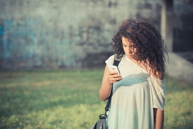 jovem linda mulher encaracolada marroquina usando smartphone