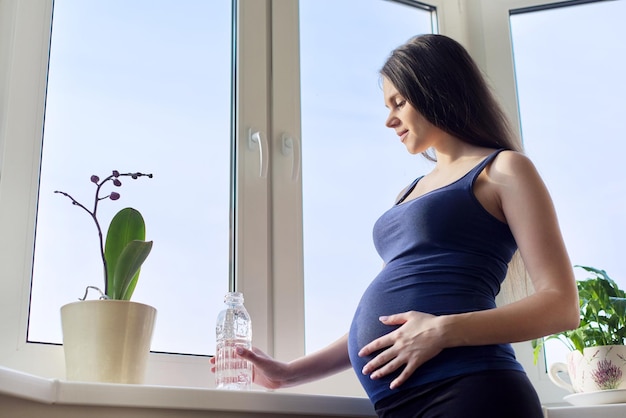 Jovem linda mulher grávida bebendo água da garrafa