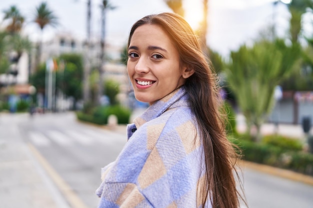 Jovem linda mulher hispânica sorrindo confiante em pé na rua