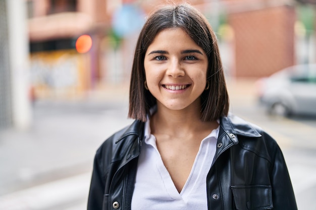 Jovem linda mulher hispânica sorrindo confiante em pé na rua