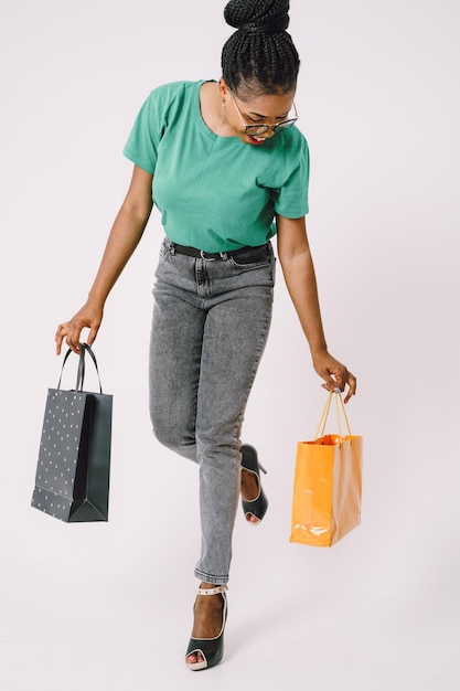 Jovem linda mulher negra carregando sacolas de compras e se sentindo animada