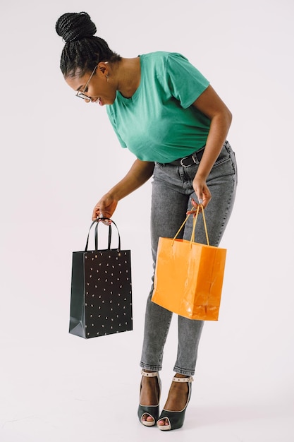 Jovem linda mulher negra carregando sacolas de compras e se sentindo animada