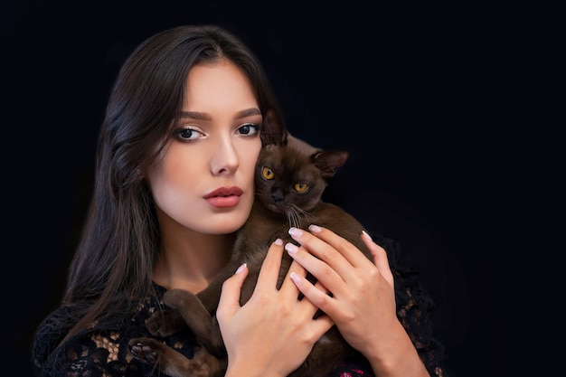 Jovem linda mulher sexy com maquiagem brilhante e um gato nas mãos