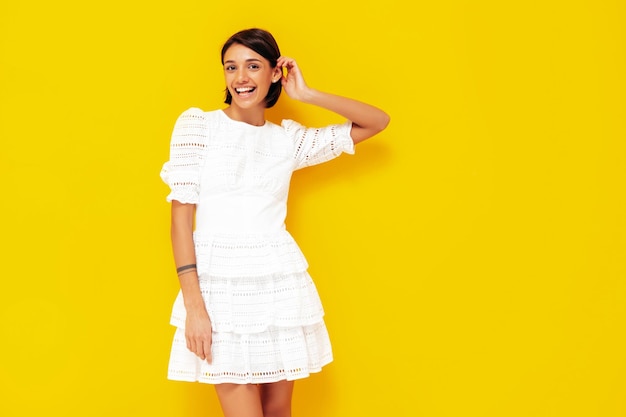 Jovem linda mulher sorridente no vestido branco de verão na moda Mulher despreocupada sexy posando perto da parede amarela no estúdio Modelo positivo se divertindo Alegre e feliz Isolado