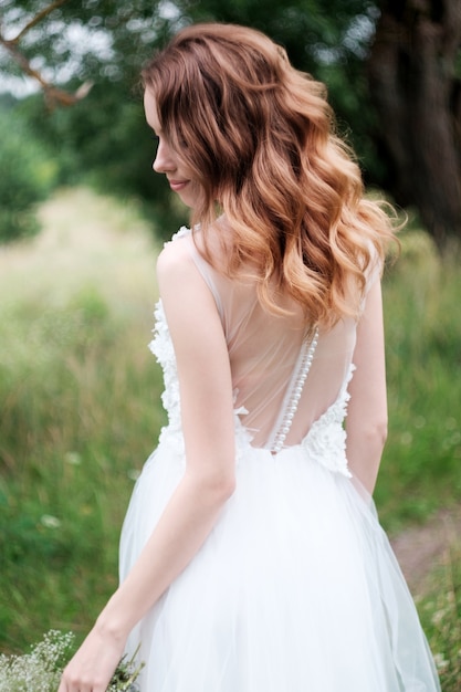 Jovem linda noiva com vestido de noiva branco ao ar livre