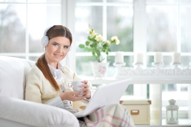 Jovem linda ouvindo música no sofá em casa