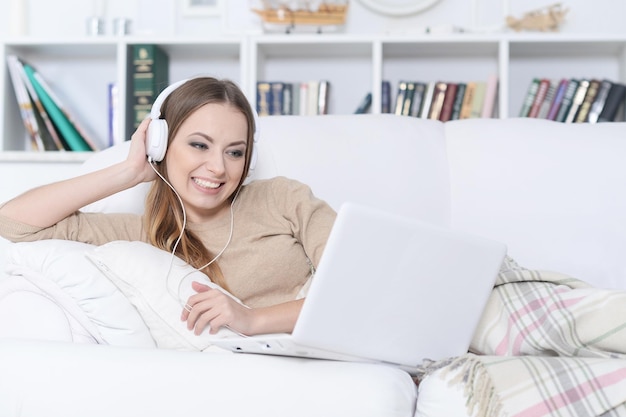 Jovem linda ouvindo música no sofá em casa