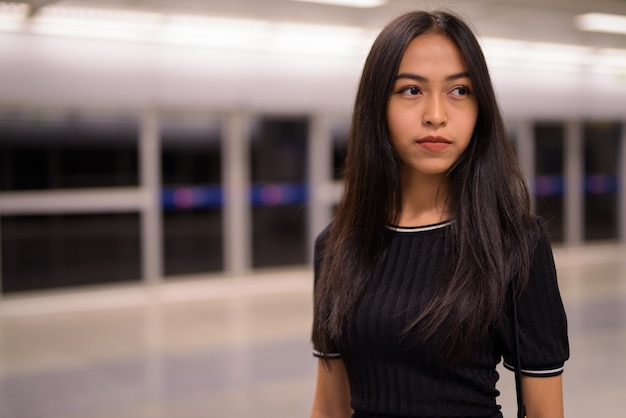 Jovem linda turista asiática pensando na estação de metrô