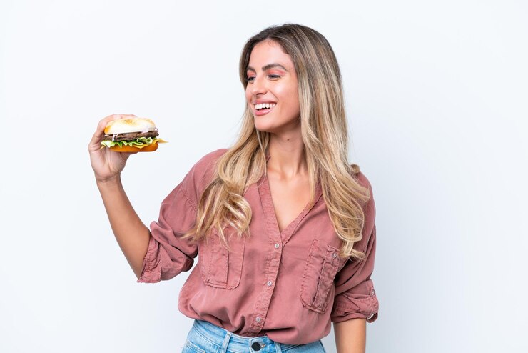 Foto jovem linda uruguaia segurando um hambúrguer isolado no fundo branco com expressão feliz