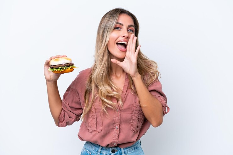 Foto jovem linda uruguaia segurando um hambúrguer isolado no fundo branco gritando com a boca aberta