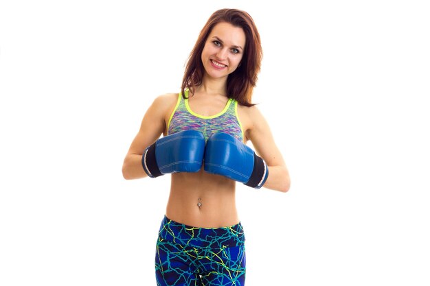 Jovem linda vestindo top esportivo colorido com luvas de boxe em fundo branco no estúdio