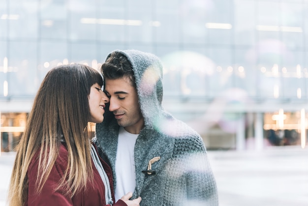 Jovem lindo casal apaixonado, abraçando-se no meio da rua de uma forma romântica com bolhas de sabão