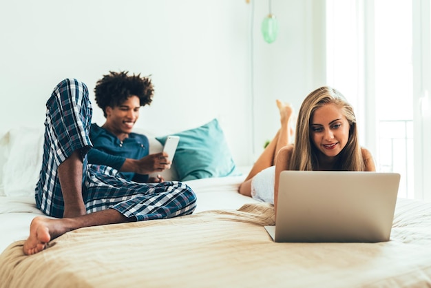 Jovem lindo casal inter-racial relaxado deitado na cama em