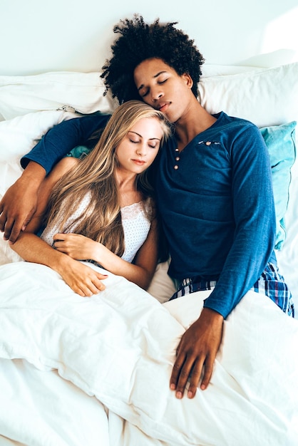 Jovem lindo casal interracial na cama dormindo