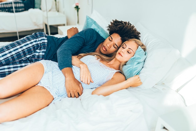 Jovem lindo casal interracial na cama dormindo