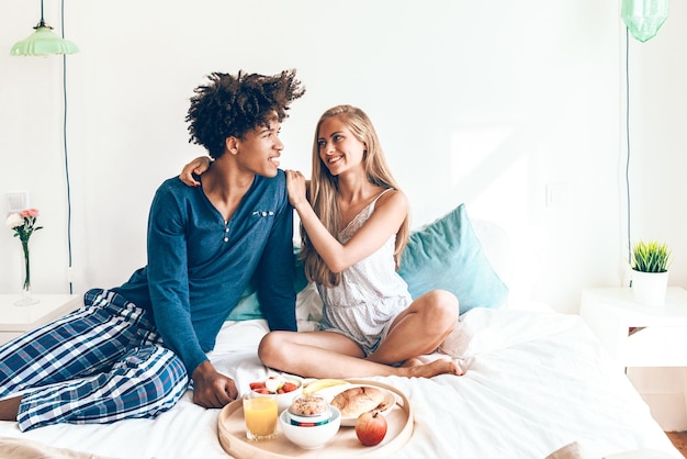 Jovem lindo casal interracial tomando um café da manhã surpresa na cama xA