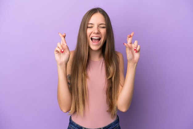 Jovem lituana isolada em fundo roxo com dedos cruzando