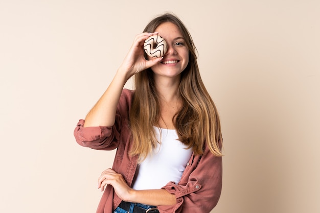 Jovem lituana isolada em um fundo bege segurando uma rosquinha e feliz