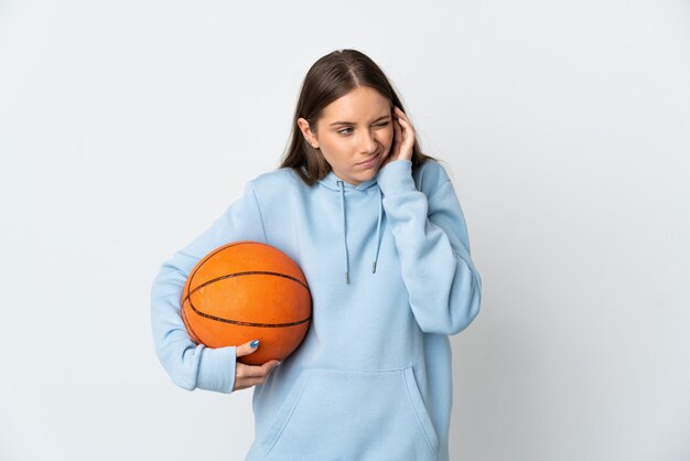 Jovem lituana jogando basquete isolada em uma parede branca frustrada e cobrindo as orelhas