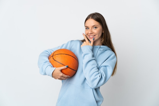 Jovem lituana jogando basquete isolado no fundo branco, feliz e sorridente