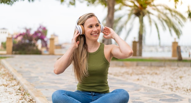 Foto jovem loira ao ar livre ouvindo música