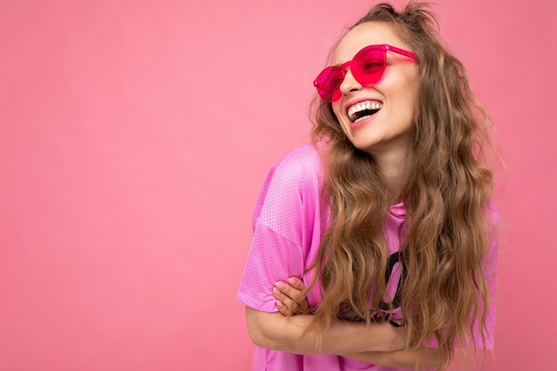 Jovem loira atraente e sorridente, usando roupas elegantes do dia a dia e óculos de sol modernos