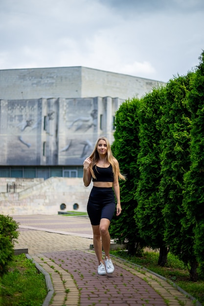 Jovem loira bonita e esportiva com uma camiseta preta e shorts esportivos justos