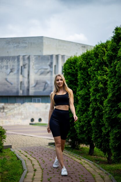 Jovem loira bonita e esportiva com uma camiseta preta e shorts esportivos justos