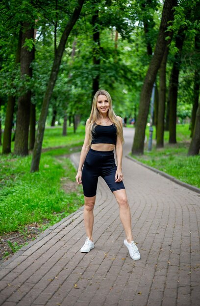 Jovem loira bonita e esportiva com uma camiseta preta e shorts esportivos justos