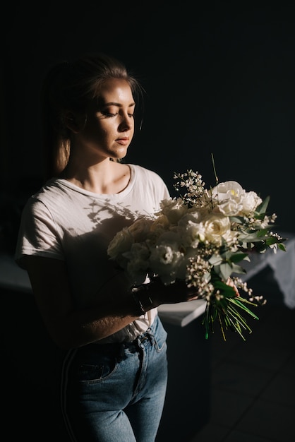 Jovem loira bonita vestindo roupas da moda segurando uma composição maravilhosa de flores frescas