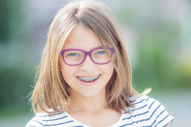 Jovem loira caucasiana bonita usando aparelho dentário e óculos