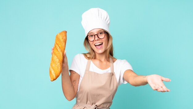 Jovem loira chef segurando uma baguete de pão