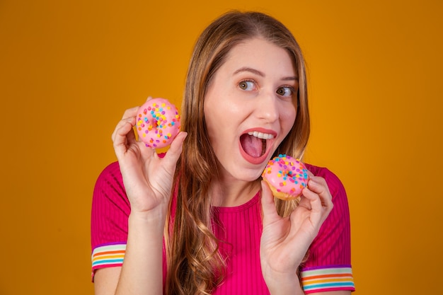 Jovem loira com donuts em fundo amarelo.