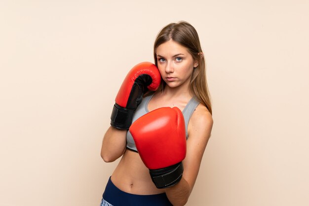 Jovem loira com luvas de boxe sobre parede isolada