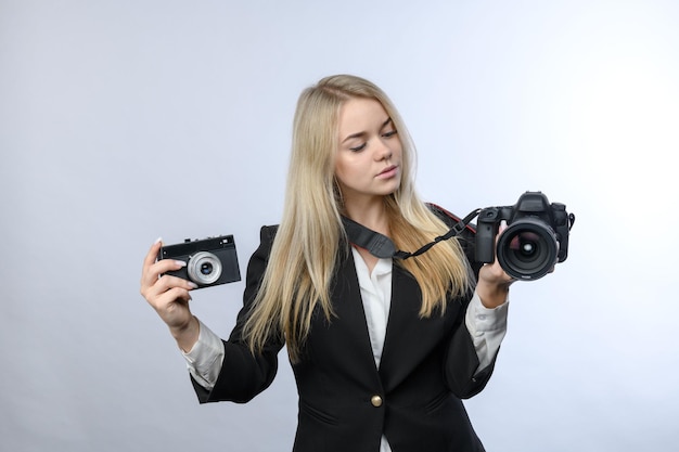 Jovem loira compara câmera de filme retrô e câmeras DSLR modernas em fundo branco