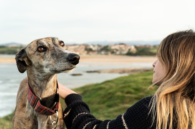 Jovem loira e seu galgo na costa