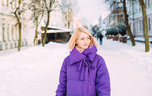 Jovem loira elegante com óculos na rua na neve