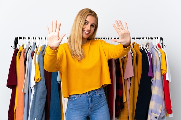 Foto jovem loira em uma loja de roupas contando dez com os dedos