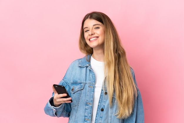 Jovem loira em uma parede isolada usando telefone celular