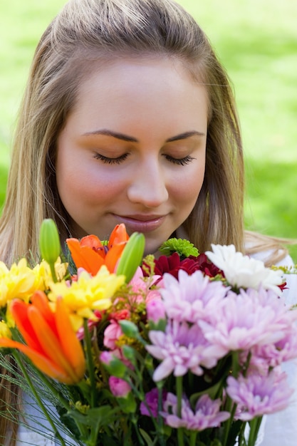 Jovem loira fechando os olhos enquanto cheirava um monte de flores