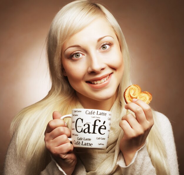 Jovem loira feliz com café e biscoitos