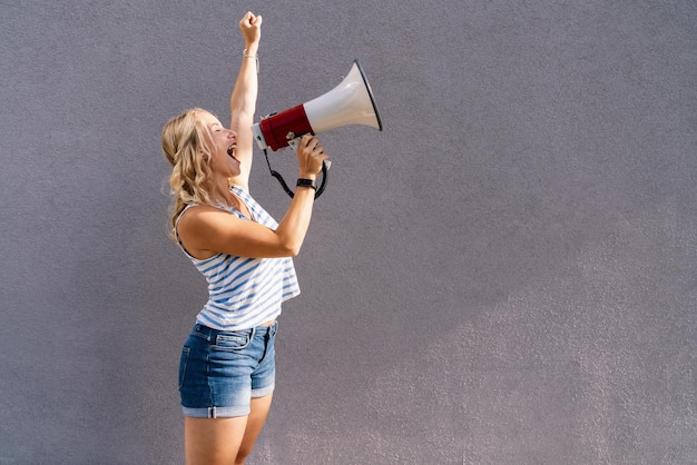 jovem loira gritando em um megafone. copyspace para seu texto individual. imagem do conceito de negócio