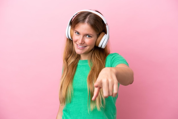 Jovem loira isolada em fundo rosa ouvindo música