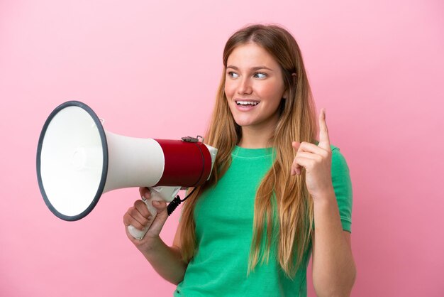 Jovem loira isolada em um fundo rosa segurando um megafone e pretendendo descobrir a solução