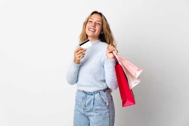 Foto jovem loira isolada no fundo branco segurando sacolas de compras e um cartão de crédito