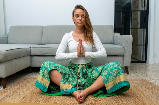 Jovem loira meditando na sala de estar em casa